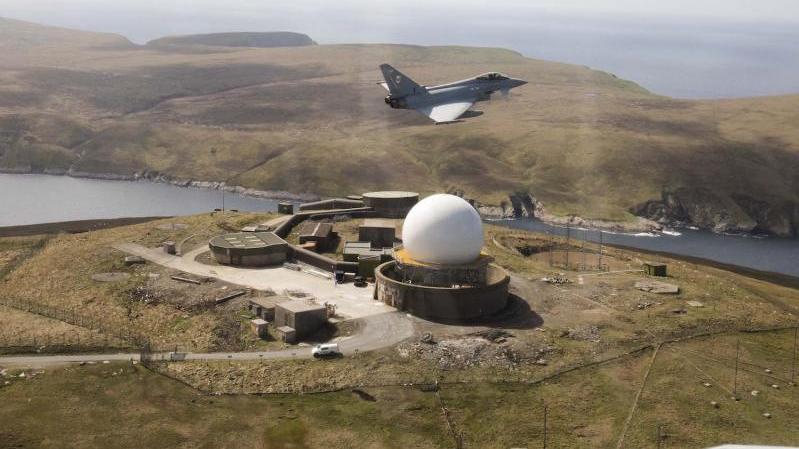 مقاتلة Eurofighter Typhoon تحلق فوق موقع رادار يتم التحكم به عن بُعد المعروف تحت مسمى RAF Saxa Vord، في المملكة المتحدة، لمراقبة الأهداف الجوية التي تحلّق فوق البحر النروجي